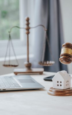 Close-up of a judge's hammer small wooden toy house On the table in the courtroom concept of real estate law division of property Land separation and divorce